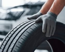 hands only. mechanic holding a tire at the repair garage. replacement of winter and summer tires