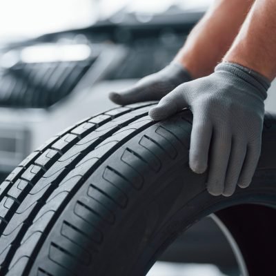 hands only. mechanic holding a tire at the repair garage. replacement of winter and summer tires